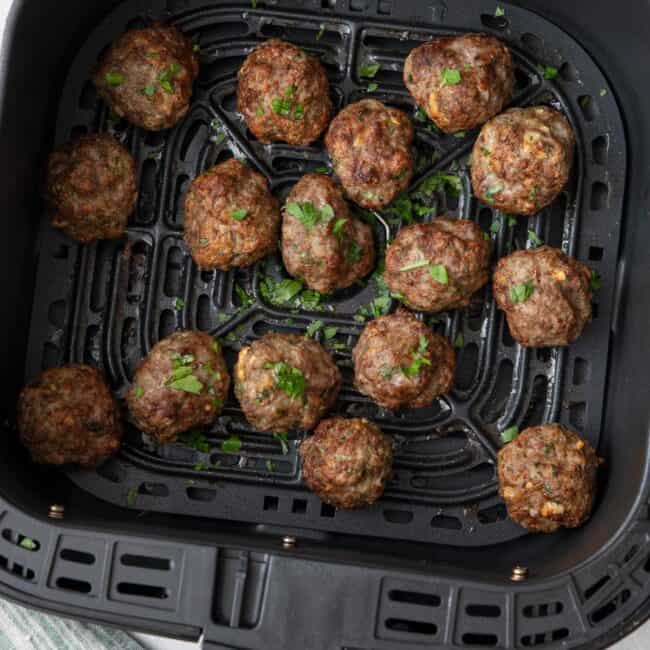 Air Fryer Meatballs after cooked in basket garnished with fresh parsley.
