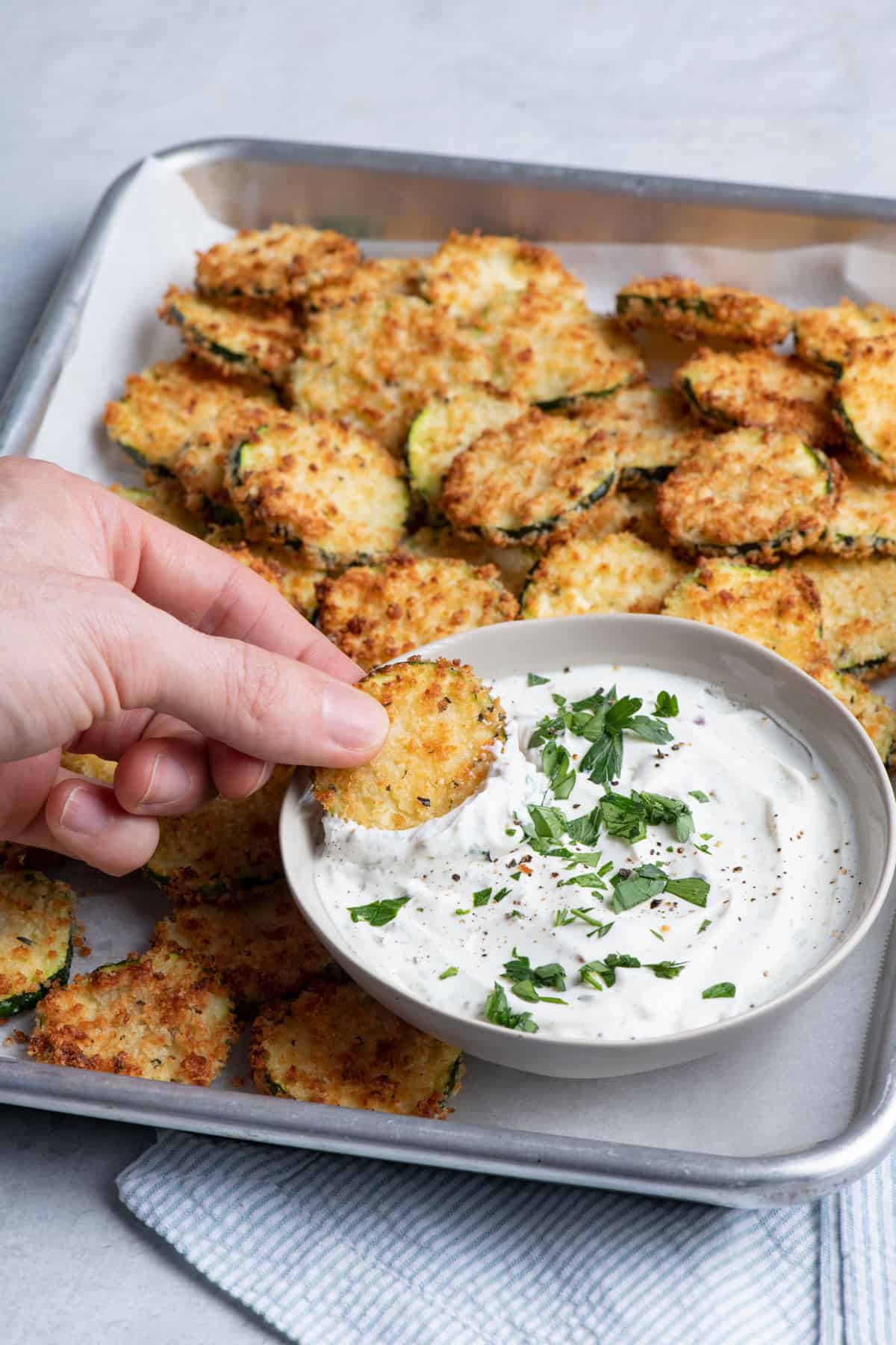 Dipping zucchini chips into sour cream dip
