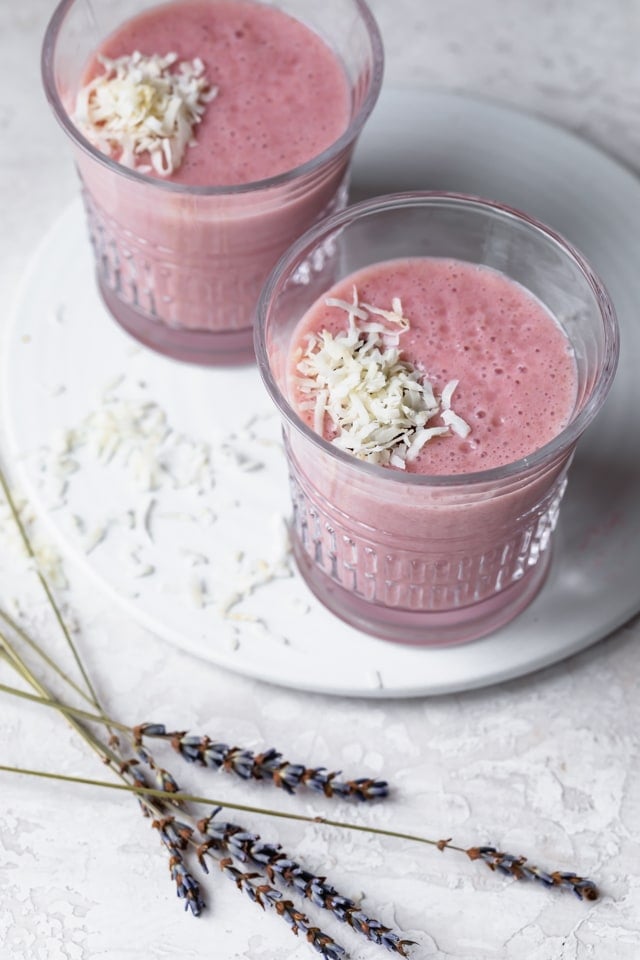 Top view of two aloe vera smoothies in clear glasses topped with shredded coconut