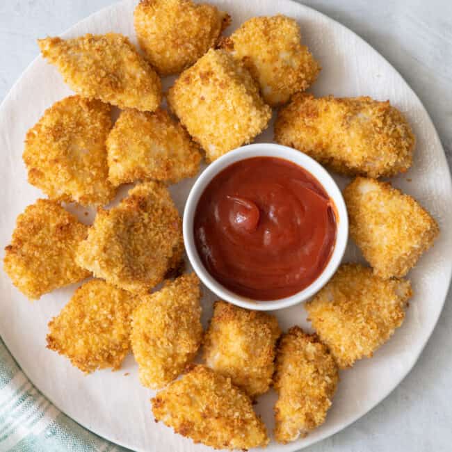 Chicken nuggets on plate with ketchup in a small pinch bowl.
