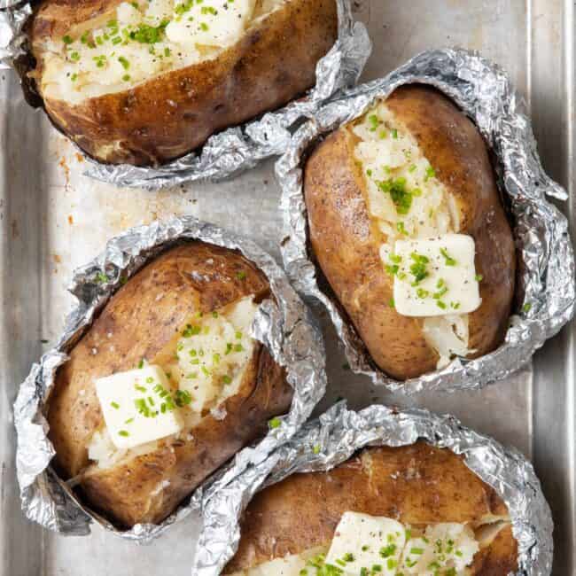 4 baked potatoes in foil split open and fluffed with a pat on butter on each and garnished with chopped chives and salt.