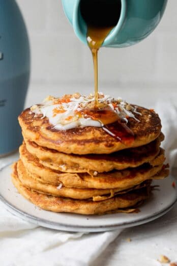 Carrot cake pancakes with maple syrup pouring on top