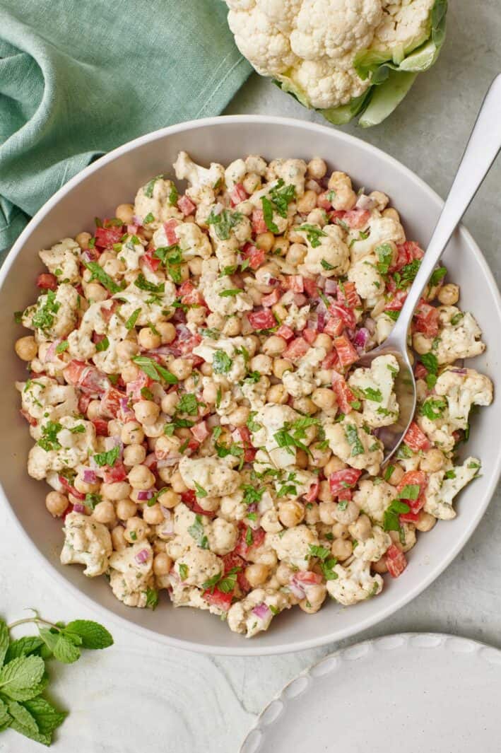 Large bowl of cauliflower salad all mixed with serving spoon inside