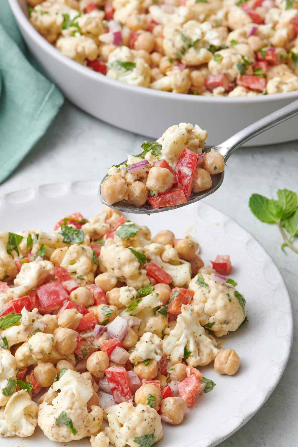 Spoon lifting up a bite of cauliflower salad with chickpeas.