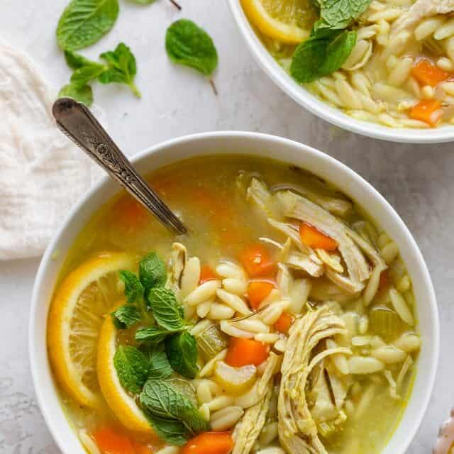 Large bowl of chicken lemon orzo soup garnished with mint