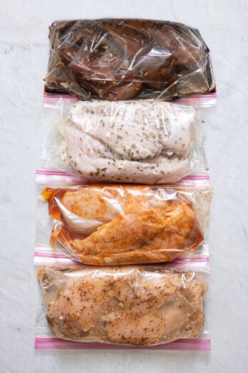 4 ziptop bags folded over with chicken breast each marinating in different recipes.