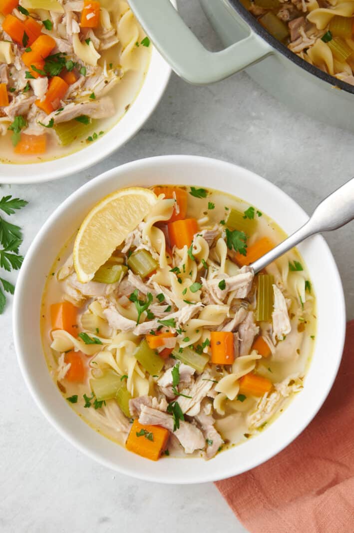 Close up view of the easy chicken noodle soup in a large bowl with lemon slices