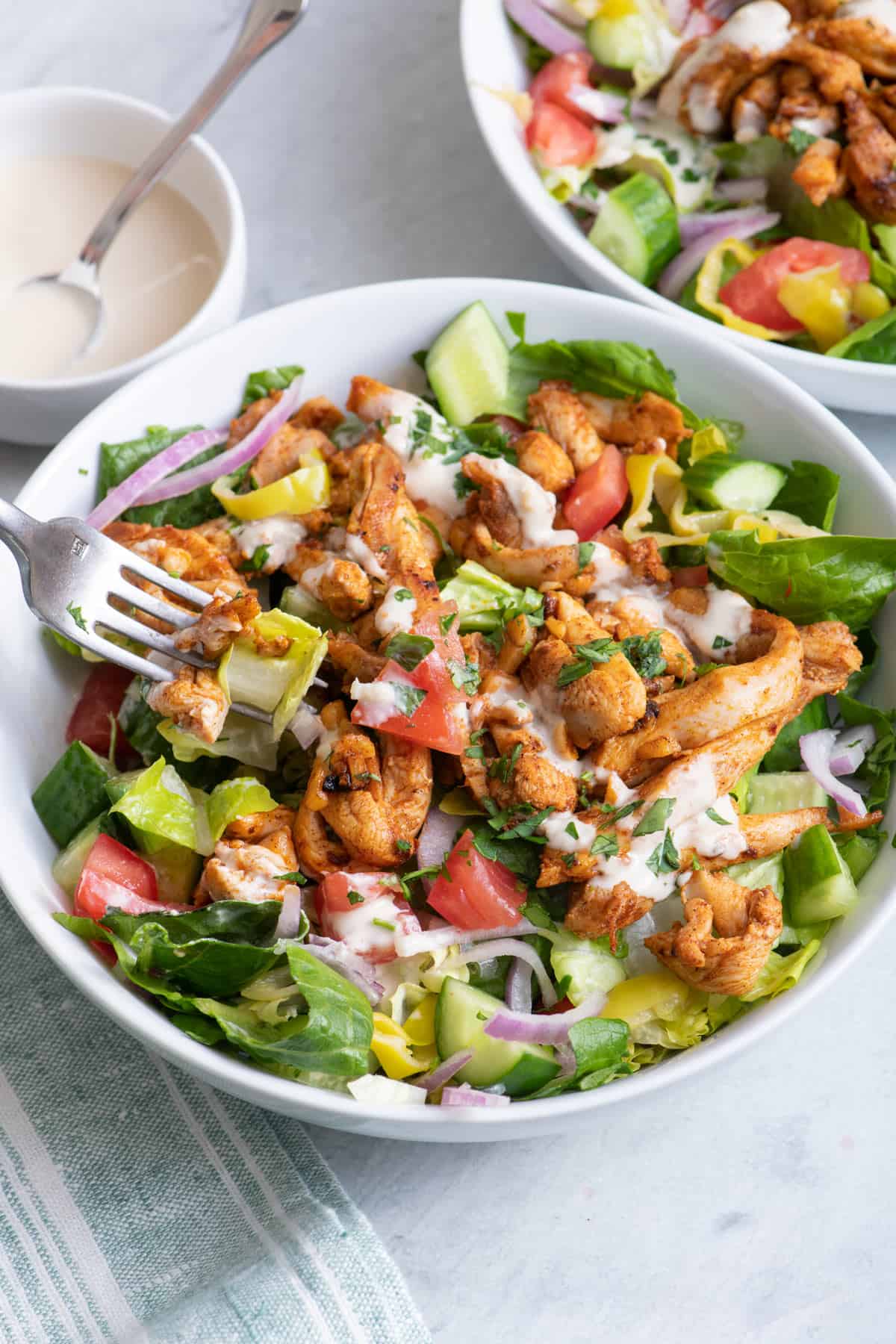 Fork taking bite out of chicken shawarma salad bowl