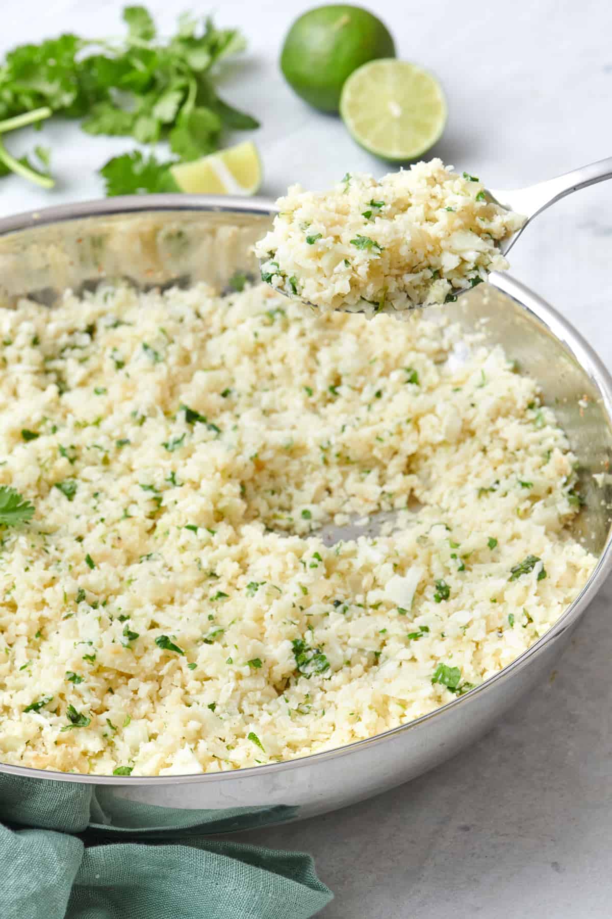 Spoon lifting up some cilantro lime rice from a skillet.