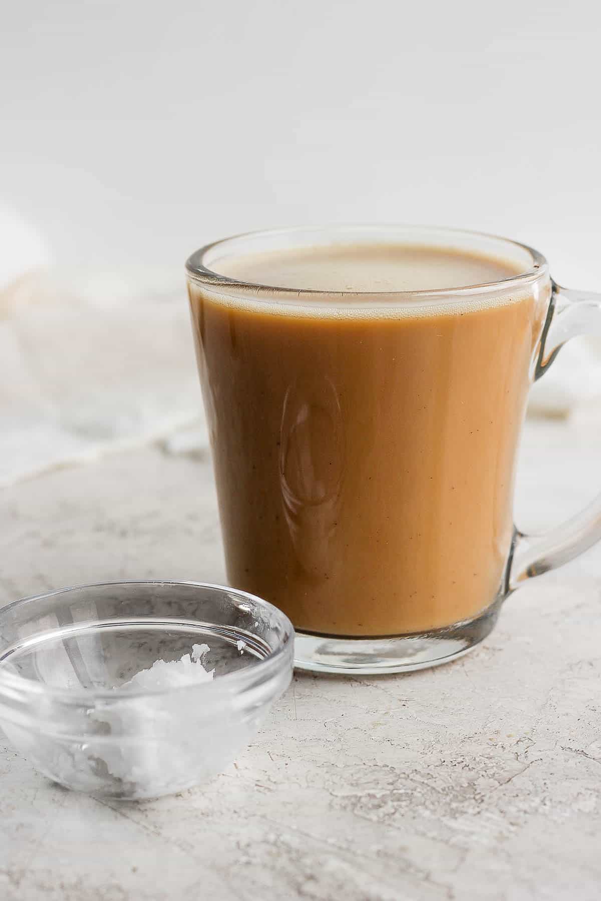 Coconut oil coffee with coconut oil next to cup