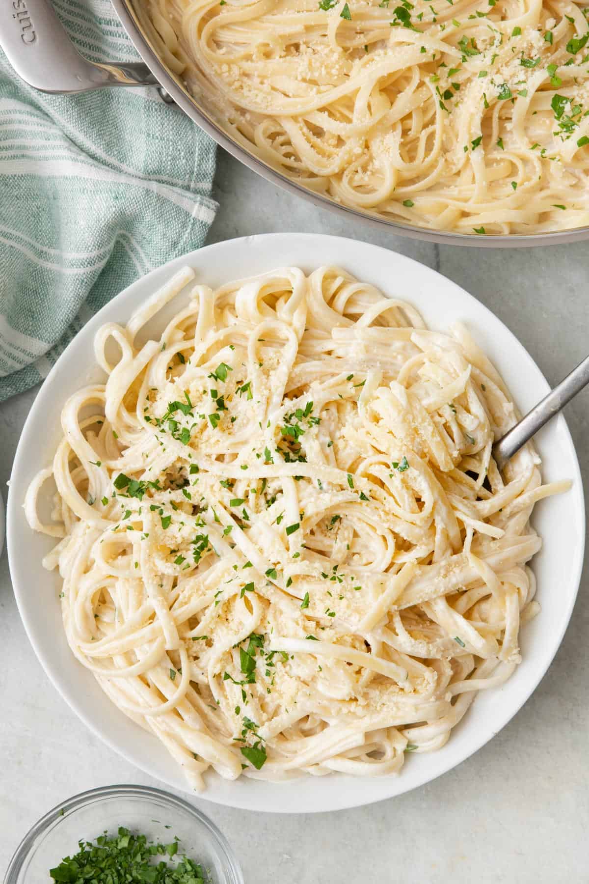 Serving of cottage cheese alfredo pasta in a bowl with pot of recipe nearby.