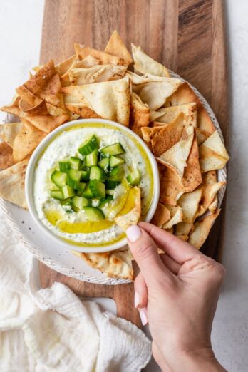 Taking a bite of the creamy feta dip using a toasted pita chip