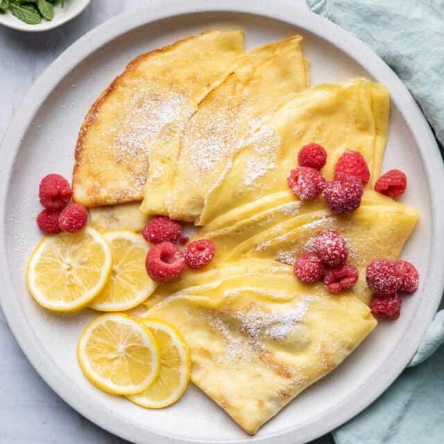 Crepes with lemon and sugar served with raspberries