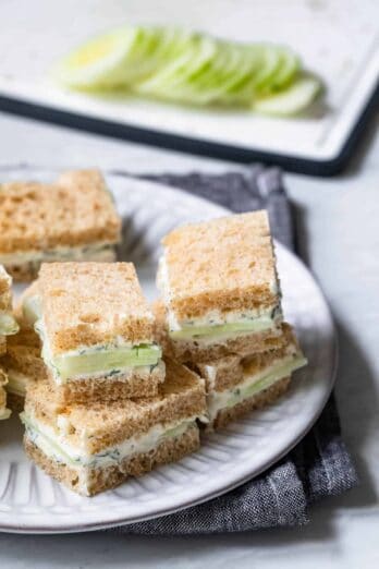 Cucumber sandwiches stacked on top of each other on plate