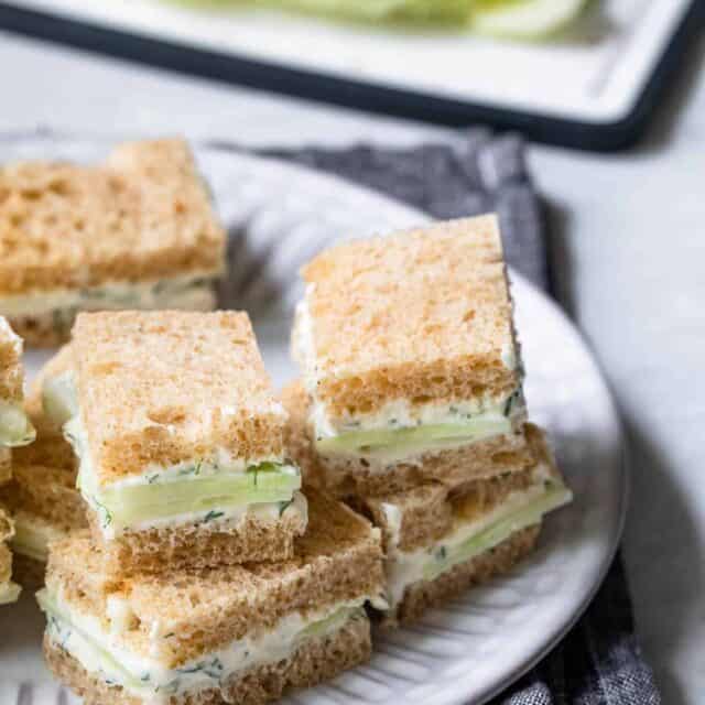Cucumber sandwiches stacked on top of each other on plate