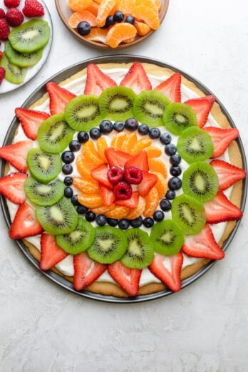 Fruit pizza decorated with strawberries, kiwi, blueberries, clementines and raspberries