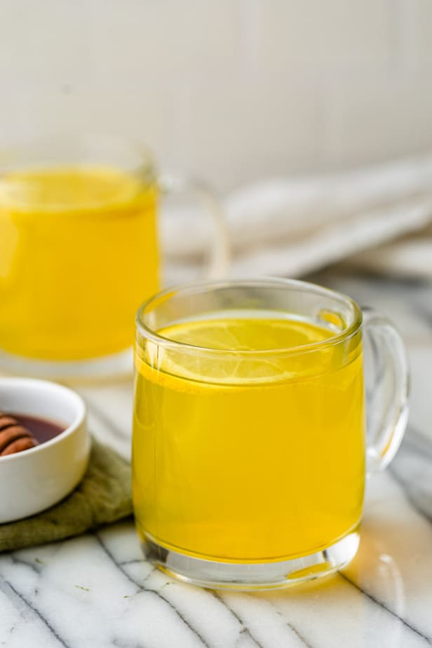A glass of Ginger Turmeric Tea with a slice of lemon