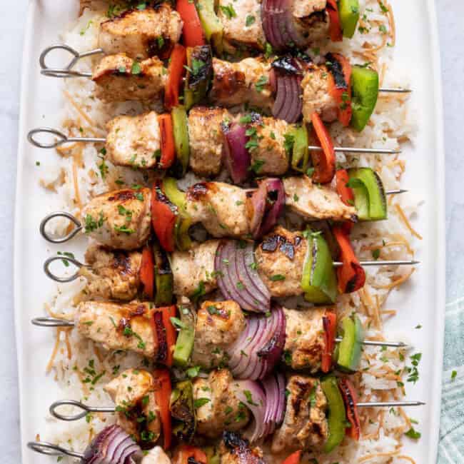 Grilled Chicken Kabobs on a white long platter served over Lebanese rice