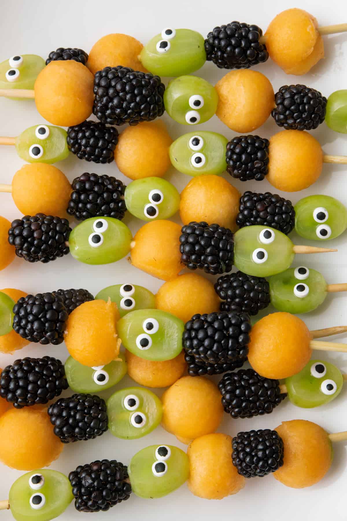 Close up of Halloween fruit kabobs on a platter with grapes, blackberries, and cantaloup.
