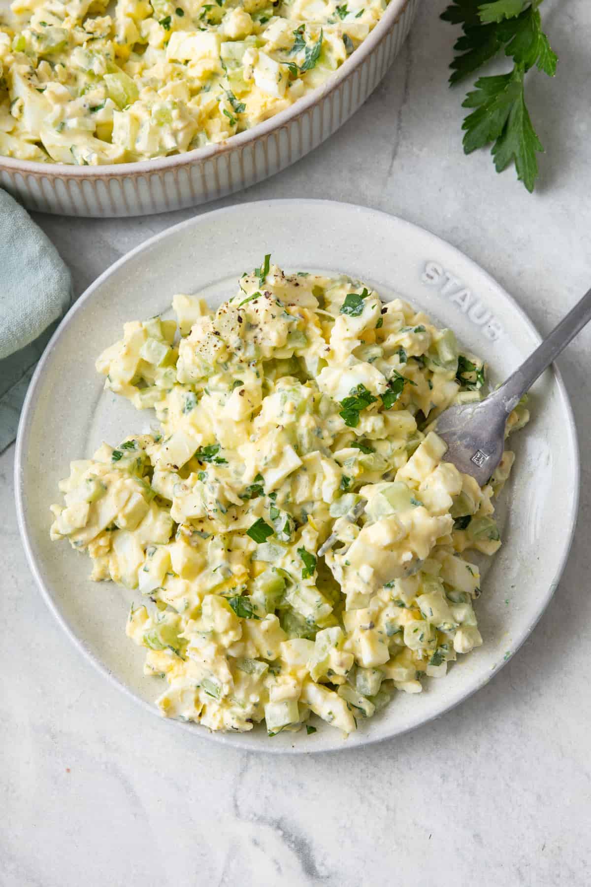 Healthy Egg Salad a a small plate with a fork resting on it, serving bowl nearby.