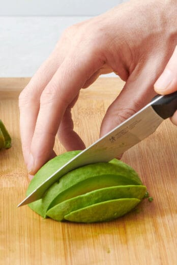 Avocado being sliced on a cutting board, closer shot