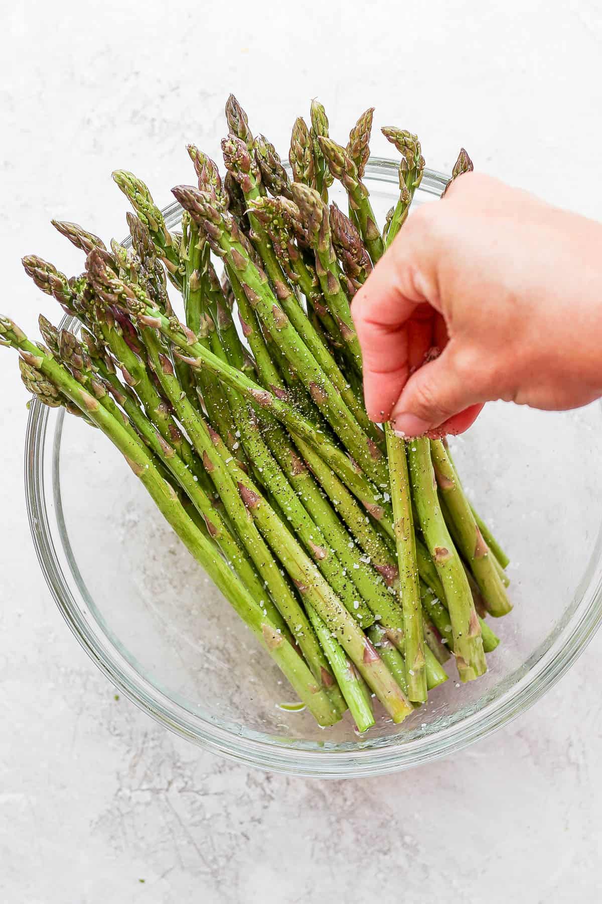 Hand seasoning asparagus before grilling