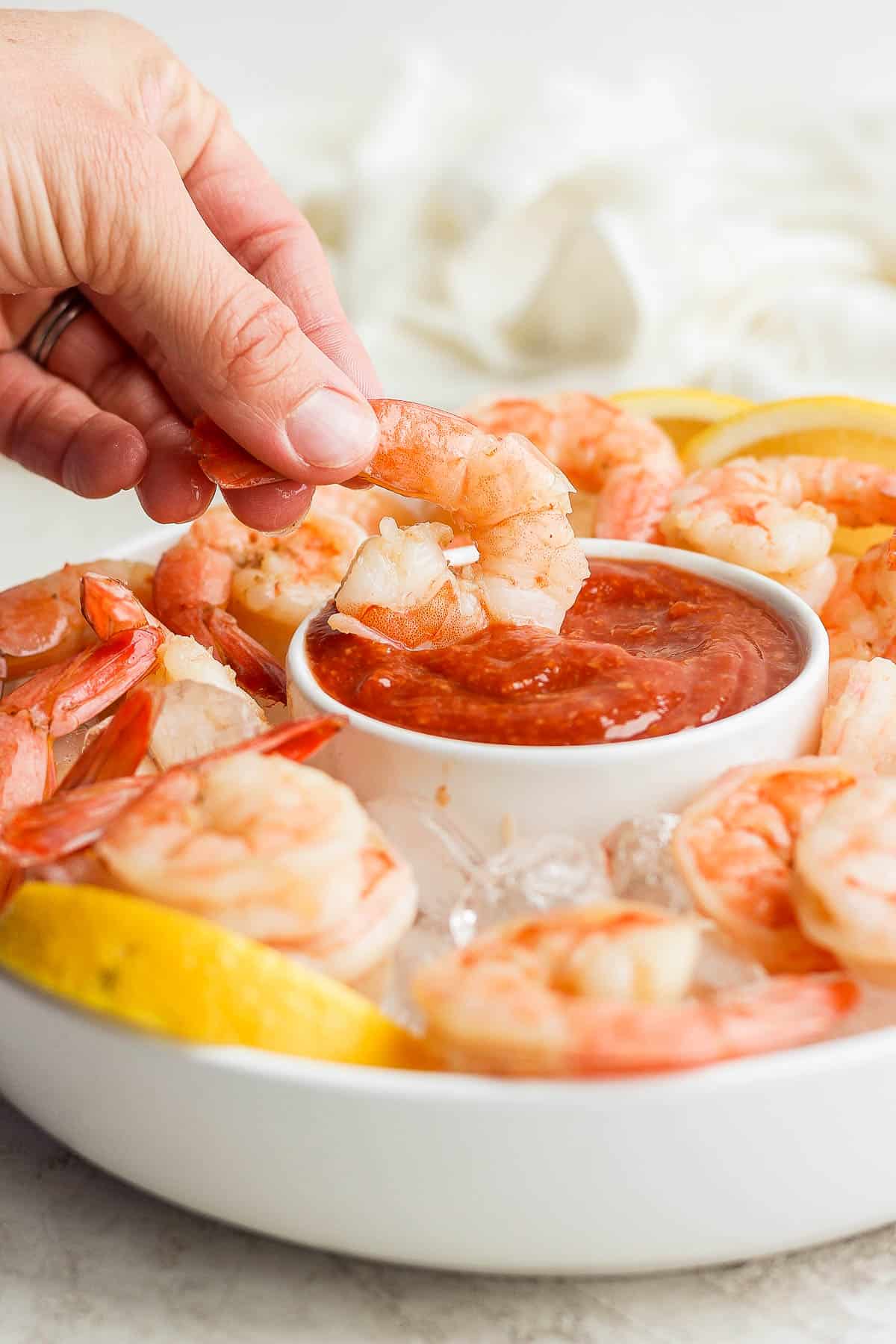 Shrimp getting dipped into cocktail sauce
