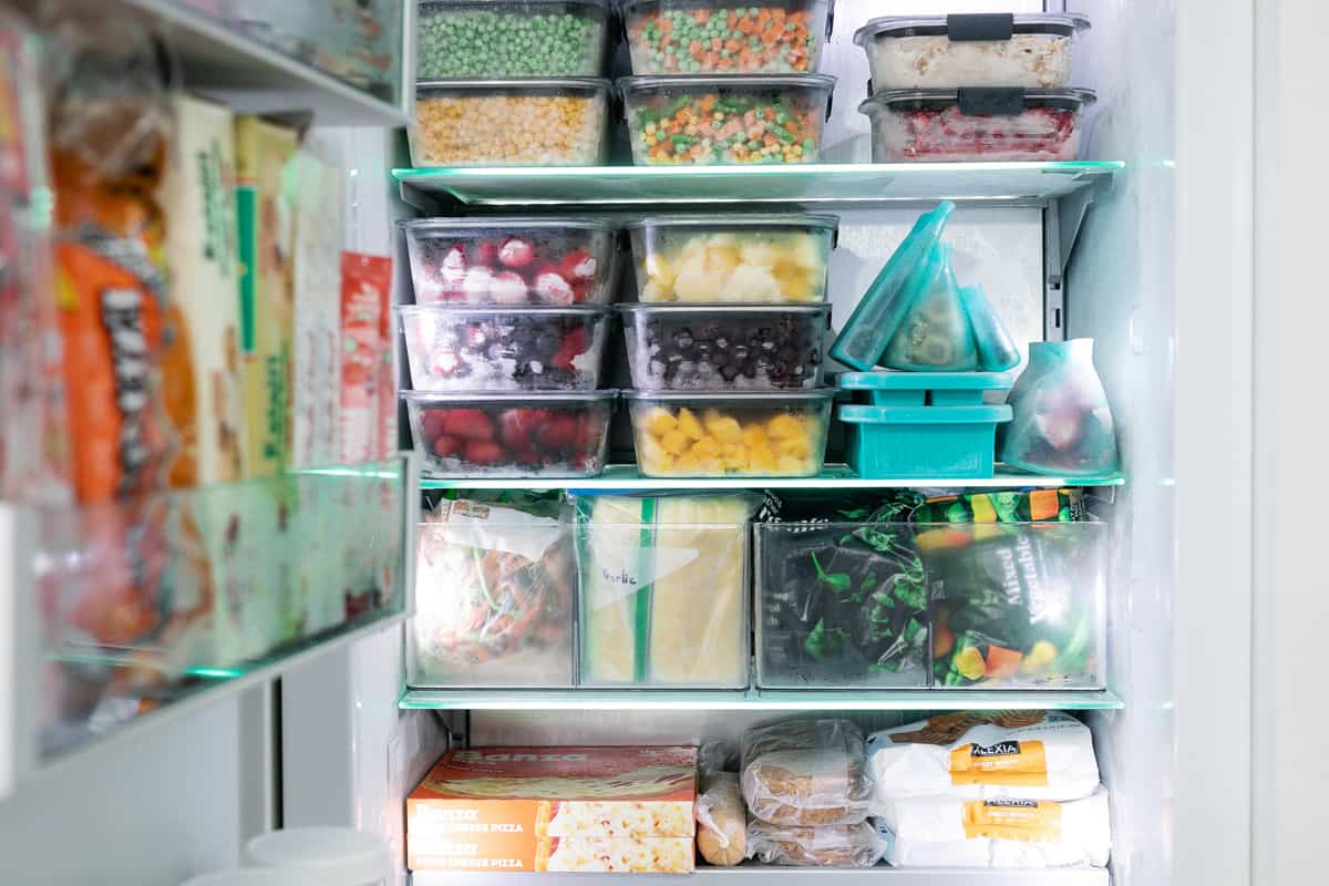 Freezer full of stackable containers and other organized containers full of fruits, veggies, and other freezer friendly foods.