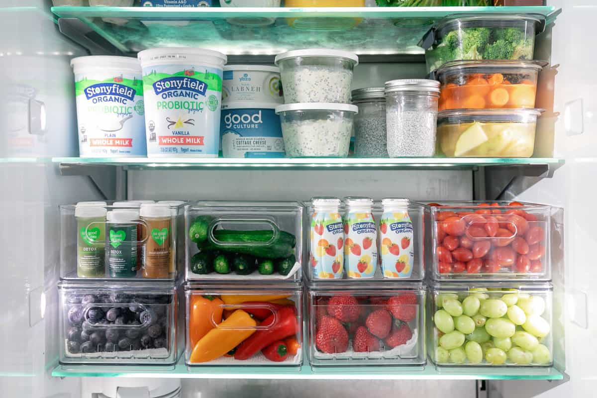 Fruits, veggies, and quick grab and go foods organized in individual containers and stacked in the fridge.