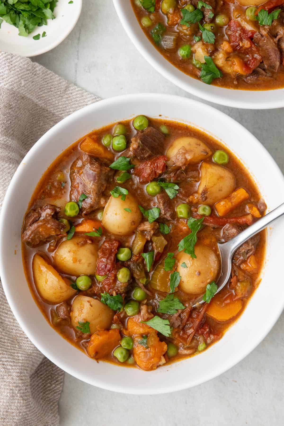Instant pot beef stew in a bowl with a spoon dipped in.