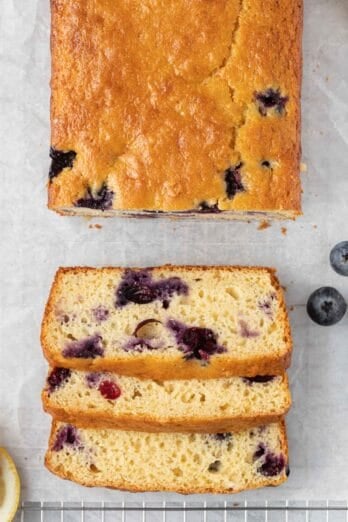 Loaf of lemon blueberry bread with three slices cut from it laying down to show the moist texture.