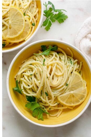 Close up overhead shot of the lemon pasta in a bowl topped with parsley and lemon slices