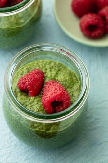 Close up shot of the pudding made with matcha tea powder topped with raspberries