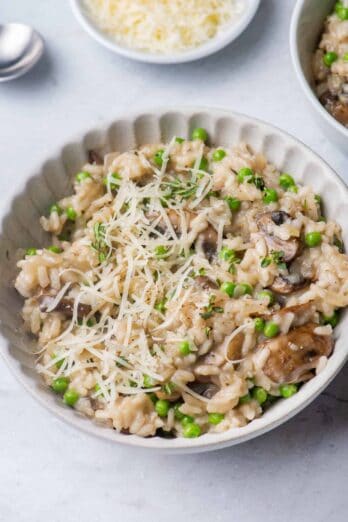 Mushroom peas risotto in a large bowl with parmesan cheese on the side