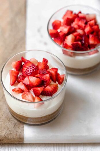 Greek Yogurt Cheesecake in two small clear glass bowls topped with strawberries