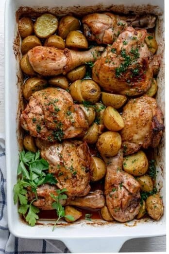 Chicken and potatoes in a pan garnished with parsley