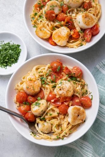 Two large bowls of pan seared scallops with cherry tomatoes and linguine pasta