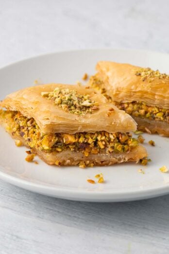 Plate with 2 pieces of baklava showing the thick pistachio layer and flaky layers.