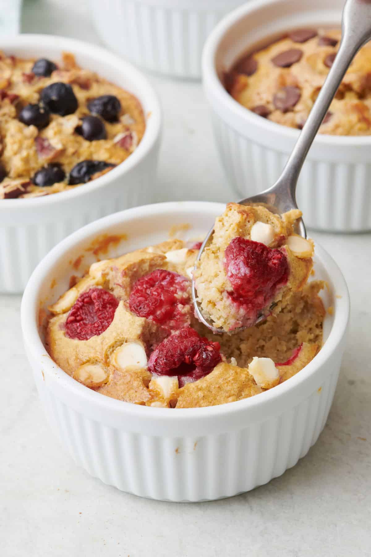Spoon lifting up a bite of the white chocolate raspberry baked oats.