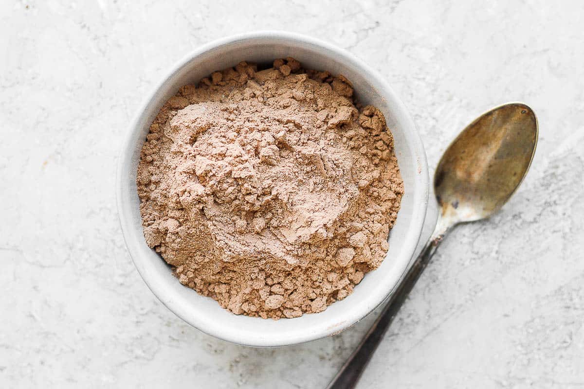 Chocolate protein powder in a bowl with a spoon next to it