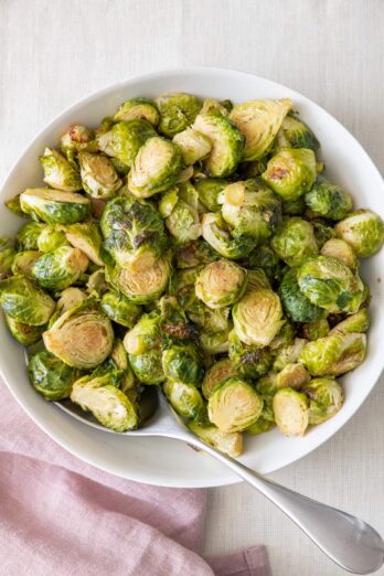 Large bowl of roasted brussel sprouts with a spoon added in.