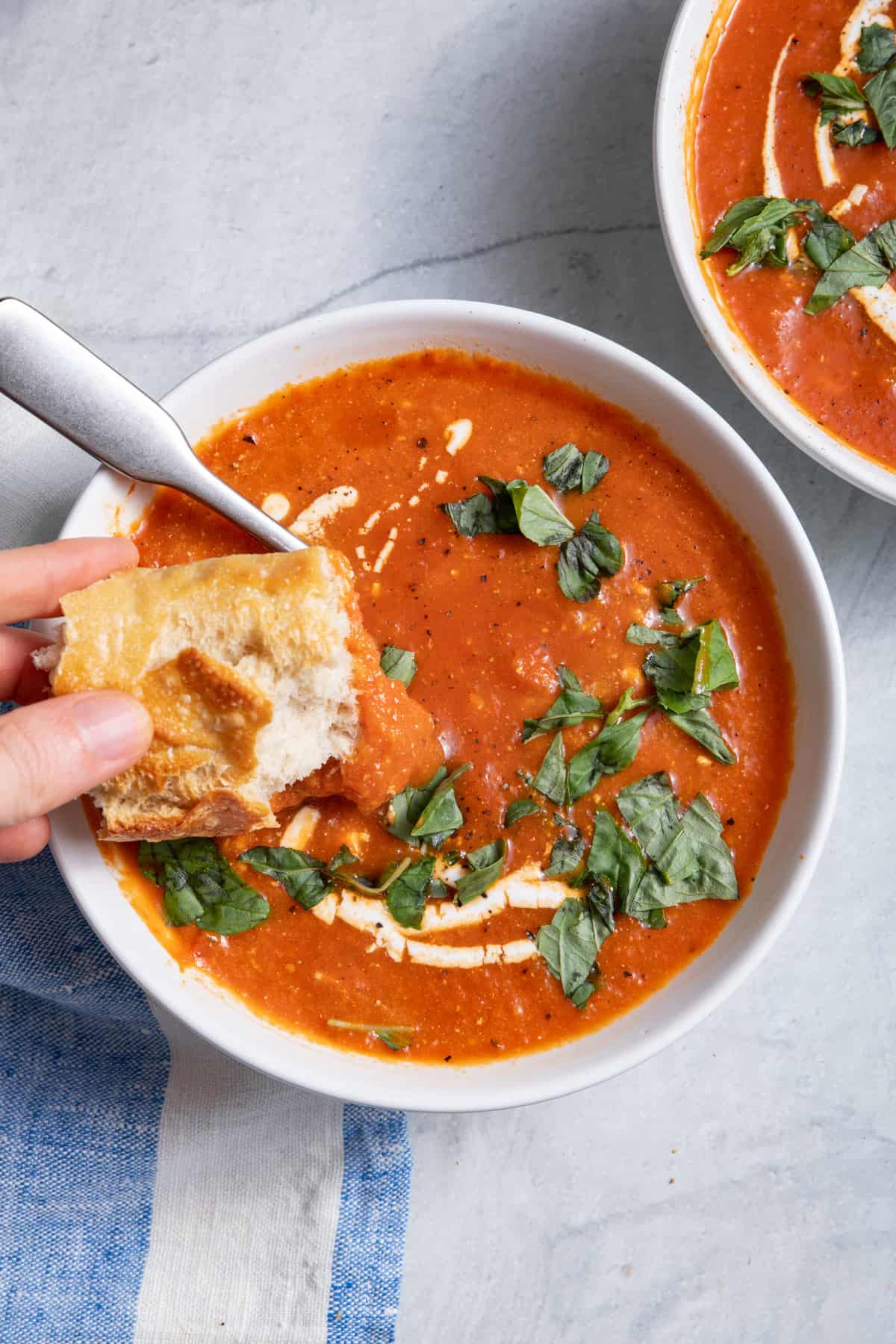 Bread dipping into bowl of roasted red pepper soup