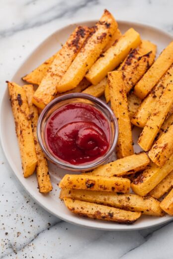 Oven baked rutabaga fries on a plate with ketchup