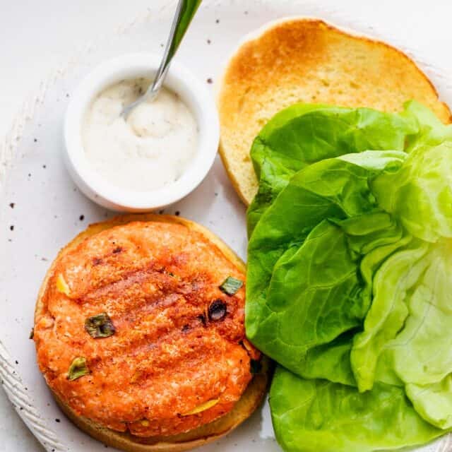 Salmon burgers made with a few ingredients and served with tartar sauce and lettuce