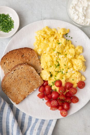 Plate with eggs, bread and tomatoes garnished with chives.