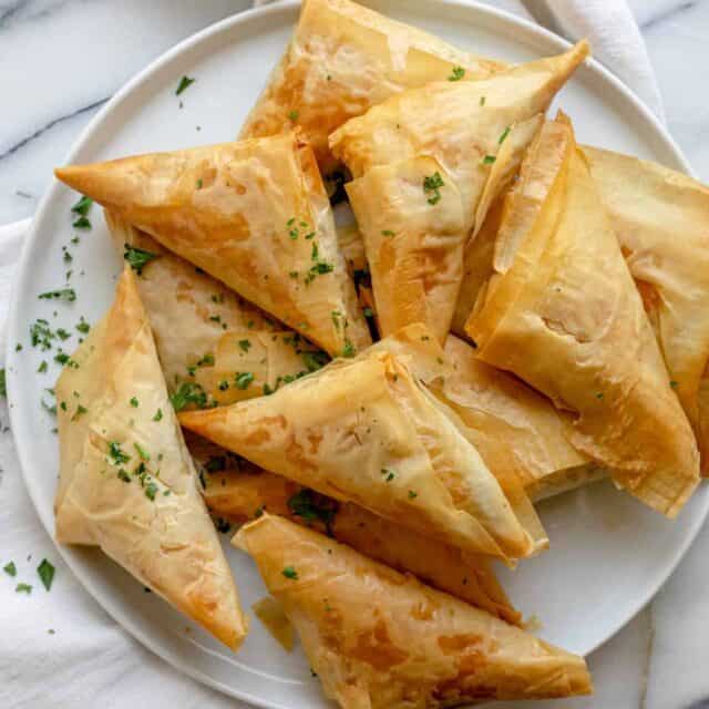 Greek spanakopita recipe made into triangles on a white plate