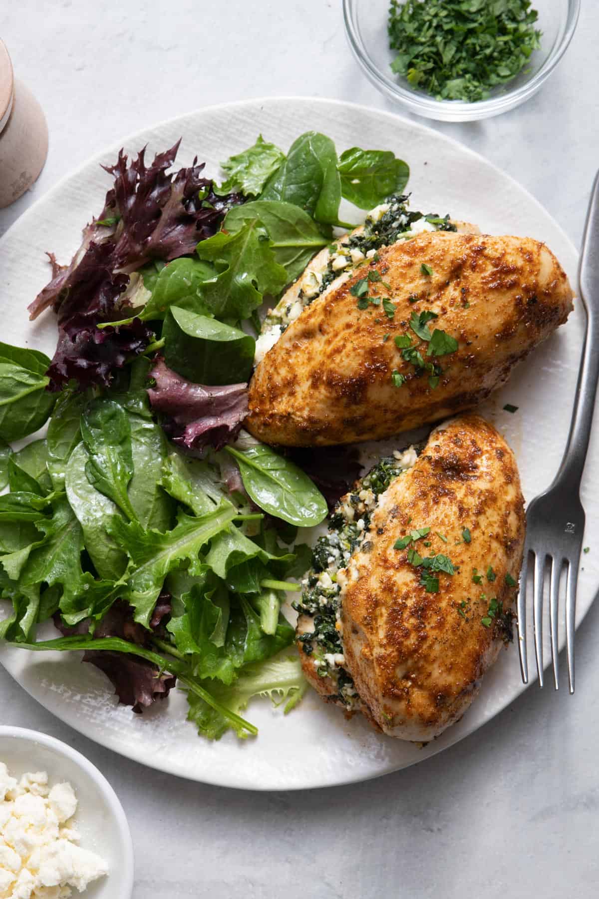 Spinach & Feta Stuffed Chicken served with mixed greens on white plate
