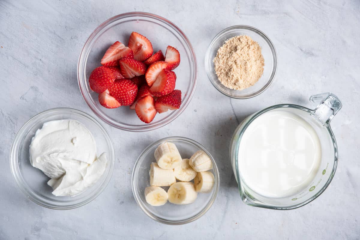Ingredients to make the smoothie: milk, strawberries, banana, greek yogurt and protein pwoder