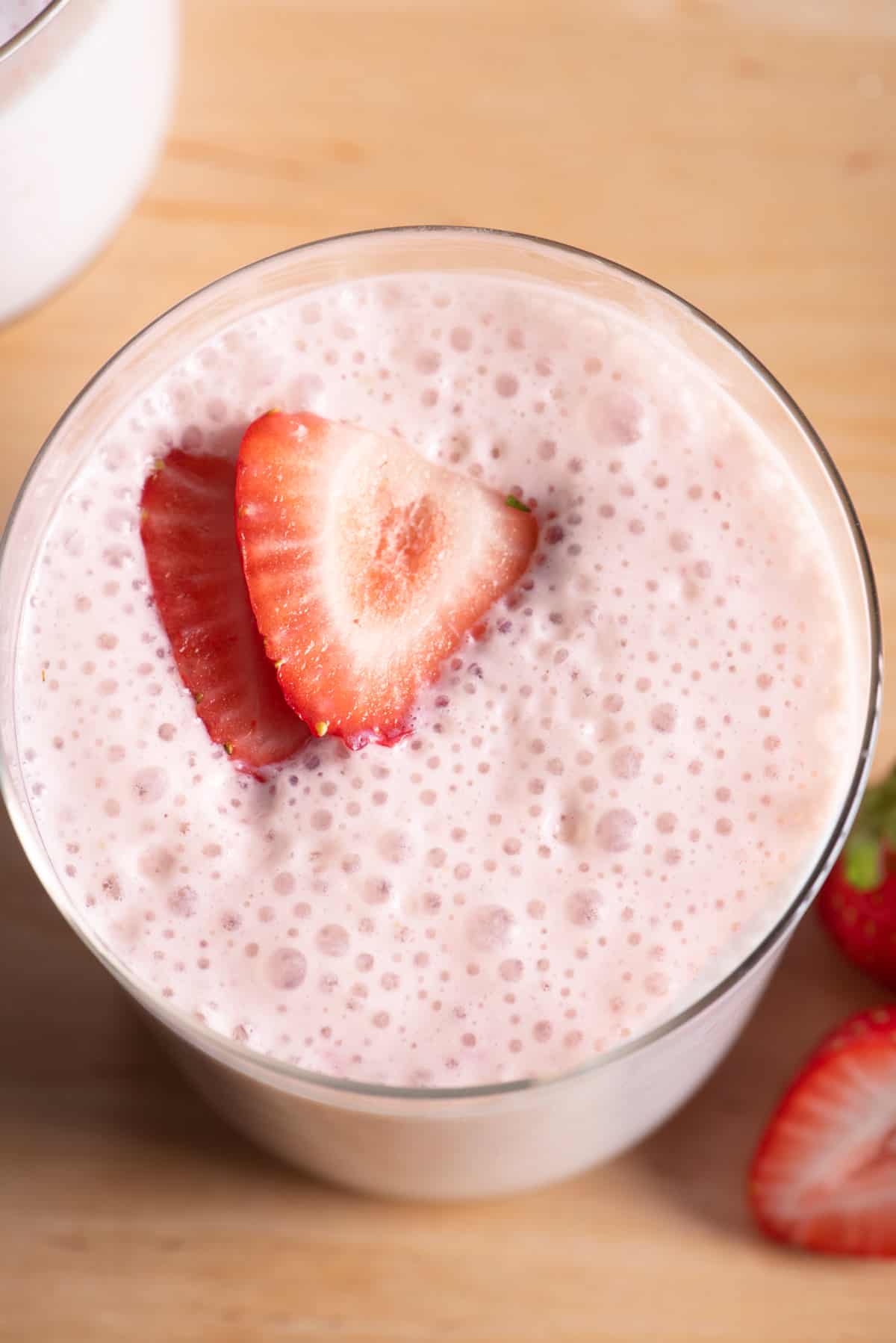 Top down view of strawberry protein smoothie with slices of strawberries on top