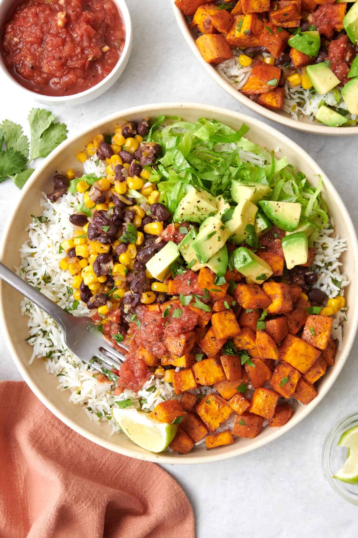 Vegetarian burrito bowl with toppings and a fork dipped inside bowl.